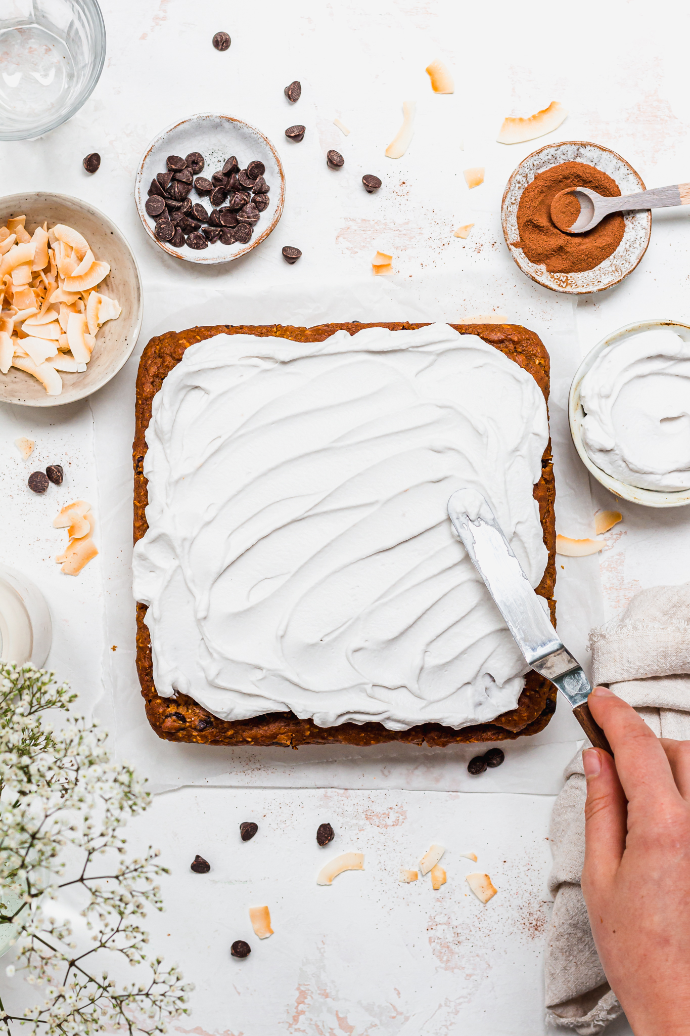 Spreading frosting on a Pumpkin Chocolate Chip and Coconut Cake