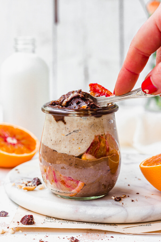 A person spooning into a jar of Chocolate Orange Blended Oats