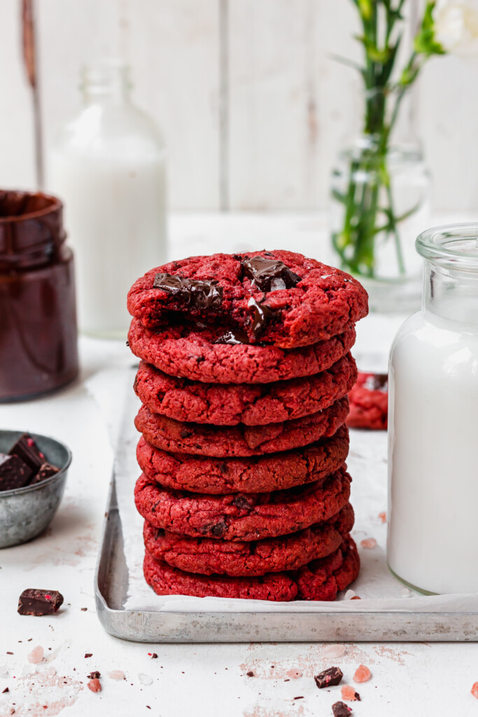 Stack of Red Velvet Chocolate Chip Cookies with a glass of milk