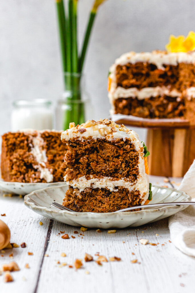 A slice of Vegan Carrot Cake with Orange Buttercream on a plate