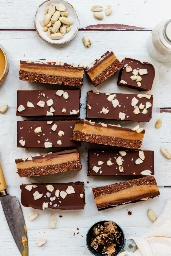 Cut up Chocolate Peanut Butter Caramel Oat Bars on a wooden backdrop