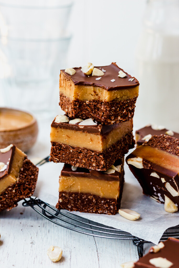 A stack of three Chocolate Peanut Butter Caramel Oat Bars on a wire rack