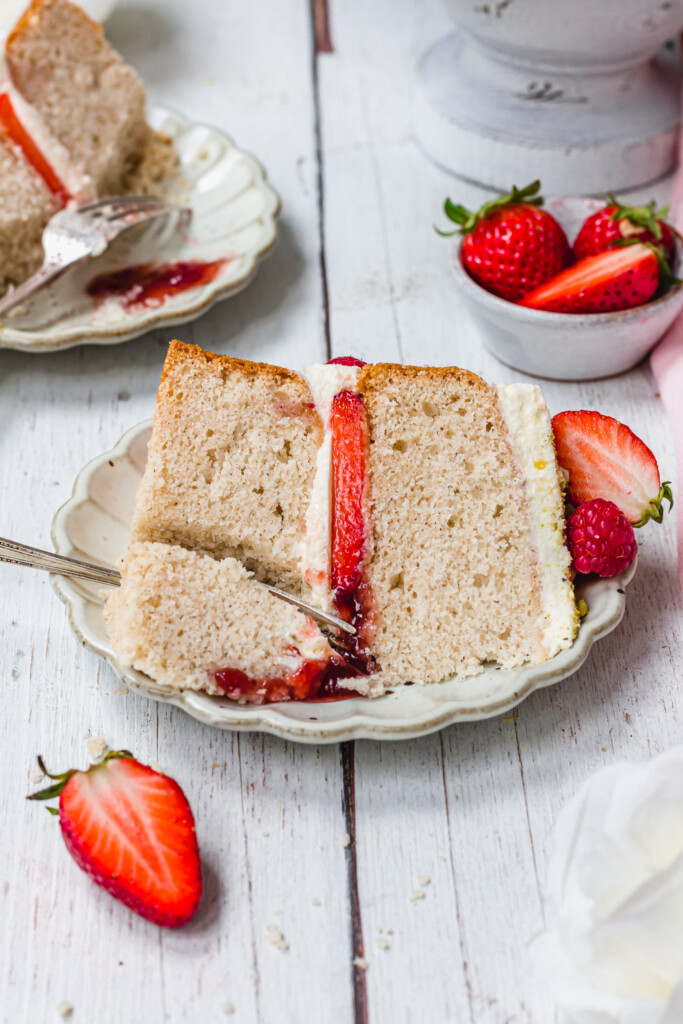A slice of Gluten-Free Vegan Victoria Sponge Cake on a small plate with a fork