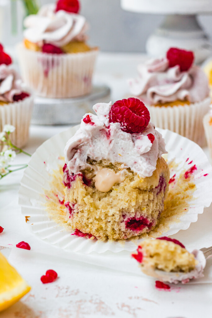 Half eaten Raspberry Lemon Custard Muffin in an open cupcake case