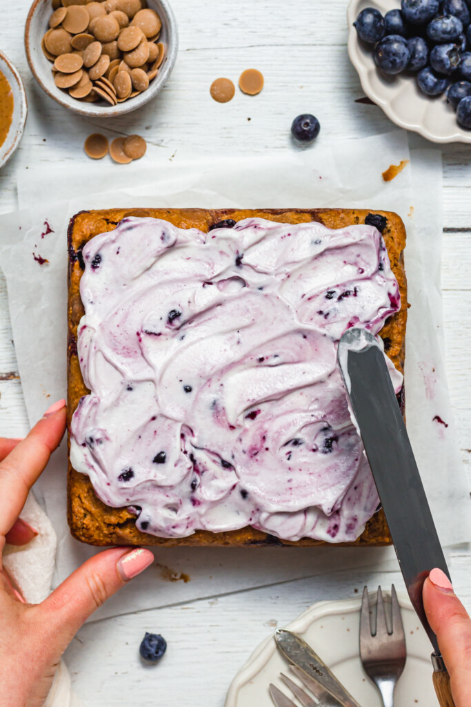 Spreading the frosting onto White Chocolate Blueberry Blondie Cake