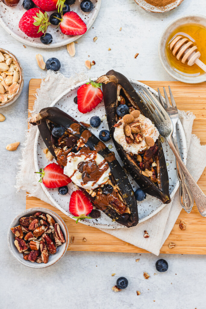 Air Fryer Banana Splits Two Ways on a small plate and wooden chopping board