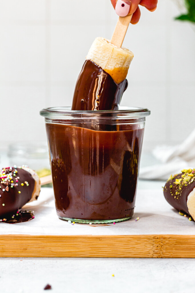 Dipping a banana into a jar of melted chocolate