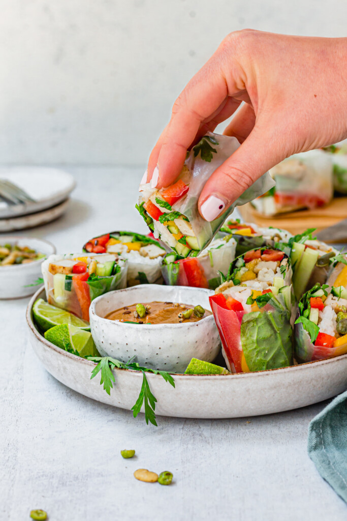 Dipping a Salt and Pepper Tofu Summer Roll into satay sauce