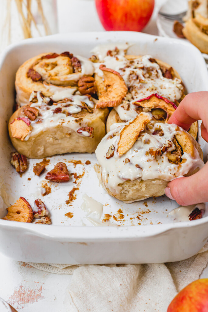 Tearing a Apple Pecan Cinnamon Roll from the dish