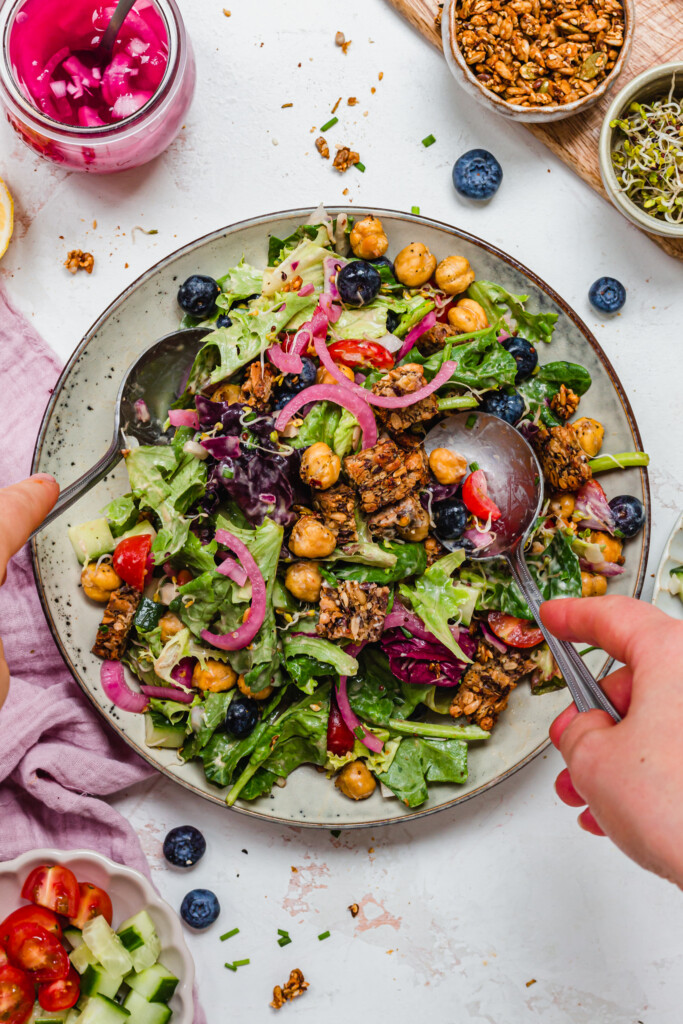 Two hands tossing a Crispy Chickpea Crouton Salad with Balsamic Dressing