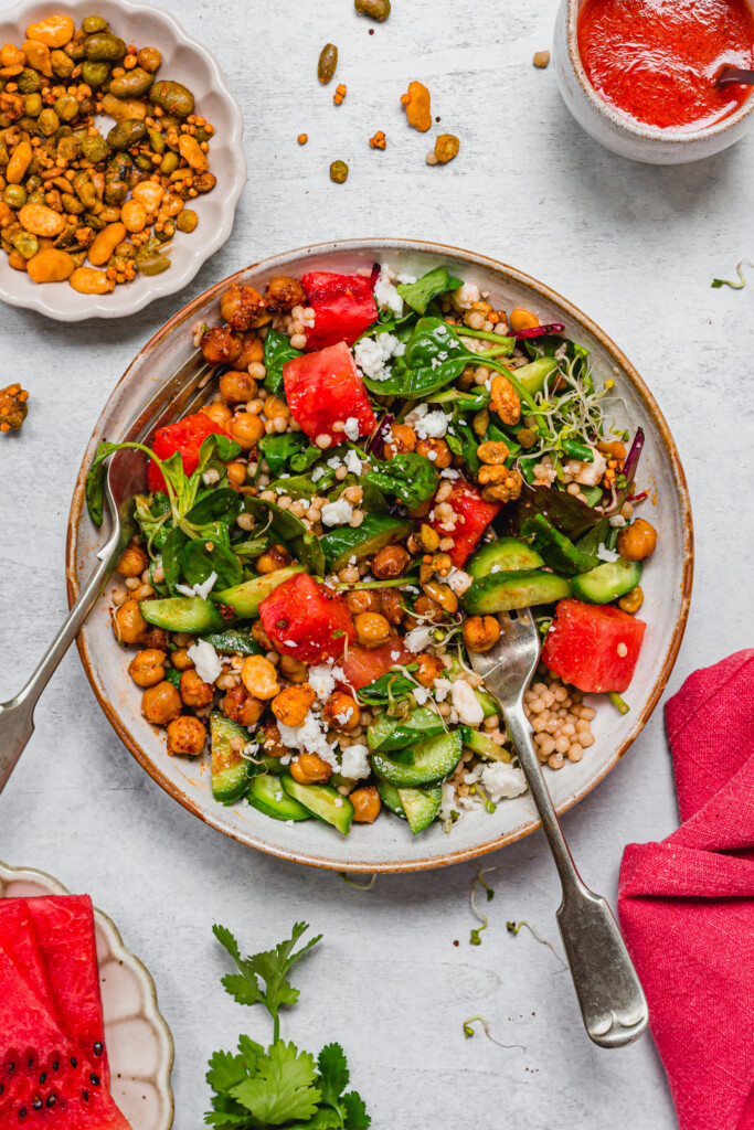 Two works tossing a BBQ Watermelon Chickpea Feta Salad