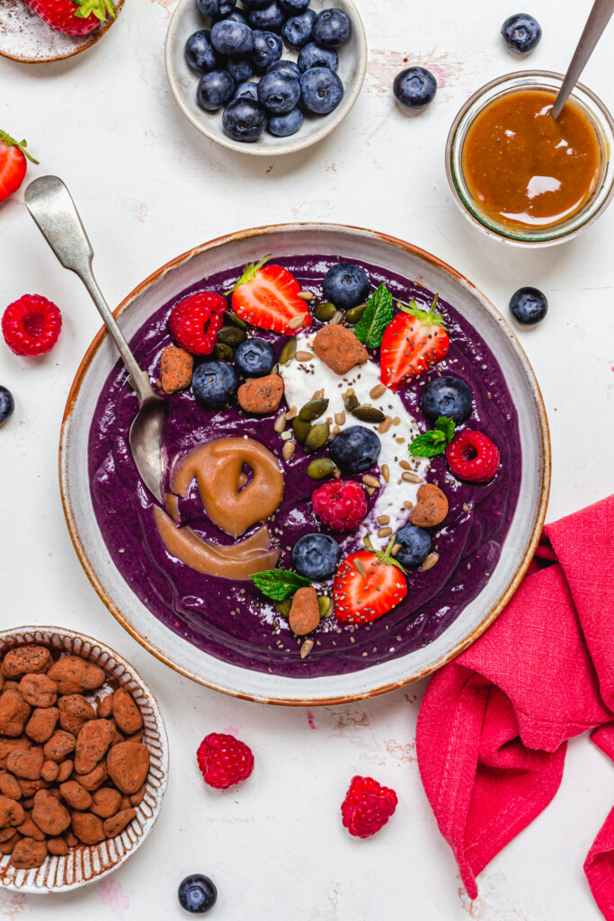 Blueberry Caramel Smoothie Bowl with a spoon and red linen