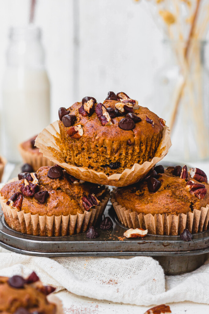 Three Chocolate Chip Pecan Pumpkin Muffins stacked in a muffin tray