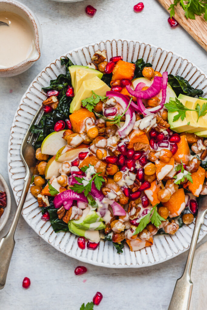 Close up of two forks in a bowl of Ginger Roasted Squash and Chickpea Salad with Tahini