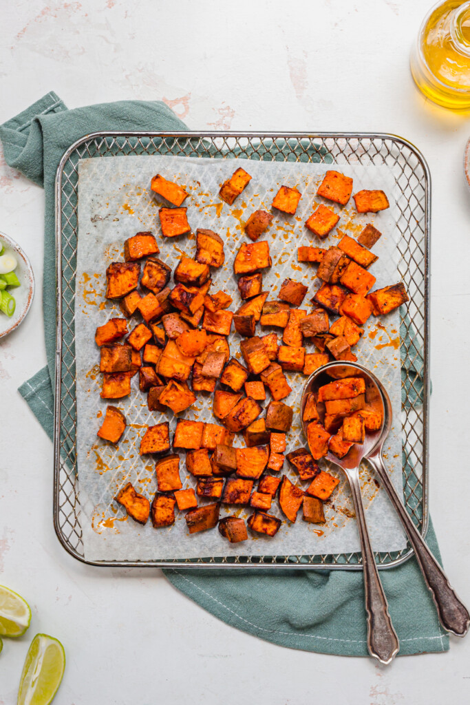 Roasted sweet potato cubes on a metal tray on a blue linen