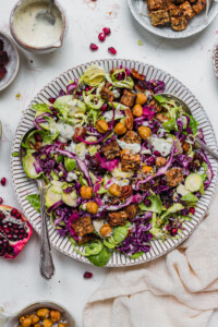 Brussel Sprout Red Cabbage Slaw with Crunchy Chickpeas with two spoons in a white bowl