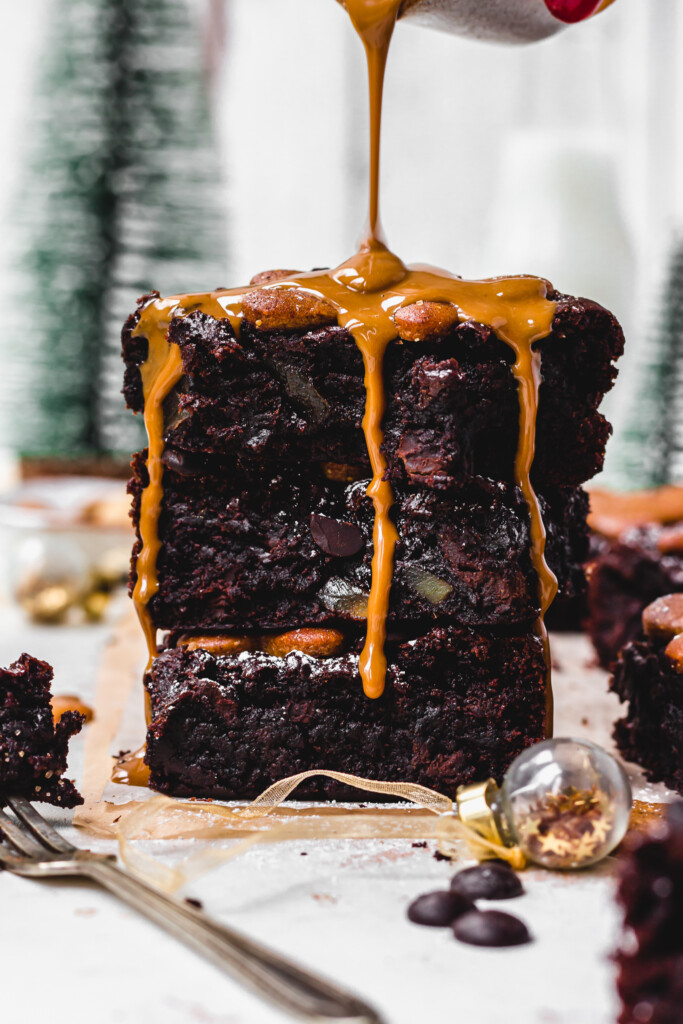 Drizzling cookie butter over a stack of three Gingerbread Fudge Brownies