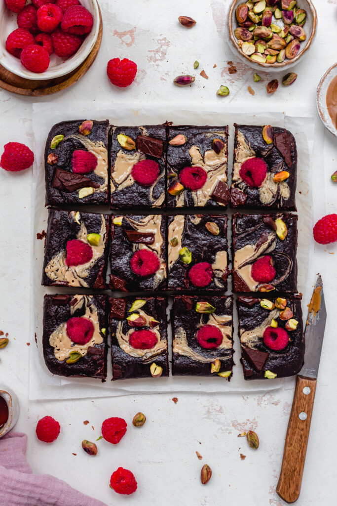Twelve Chocolate Fudge Quinoa Brownies with a knife and raspberries