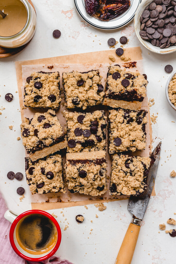 Nine squares of Mocha Date Caramel Oat Bars on a board with a knife