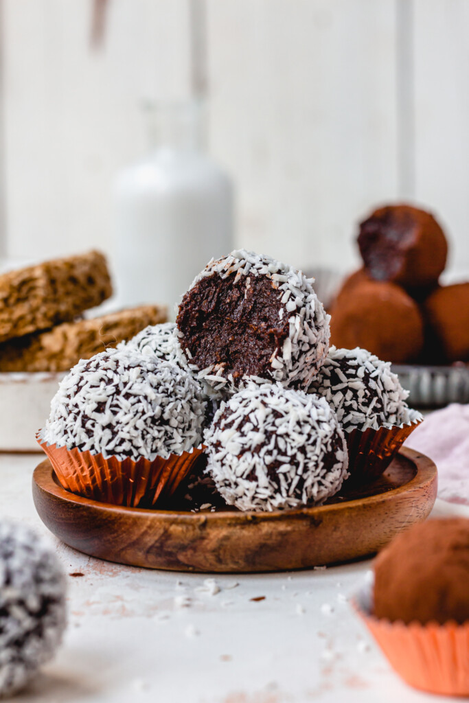 A wooden small plate of coconut covered Chocolate Weetabix Protein Balls