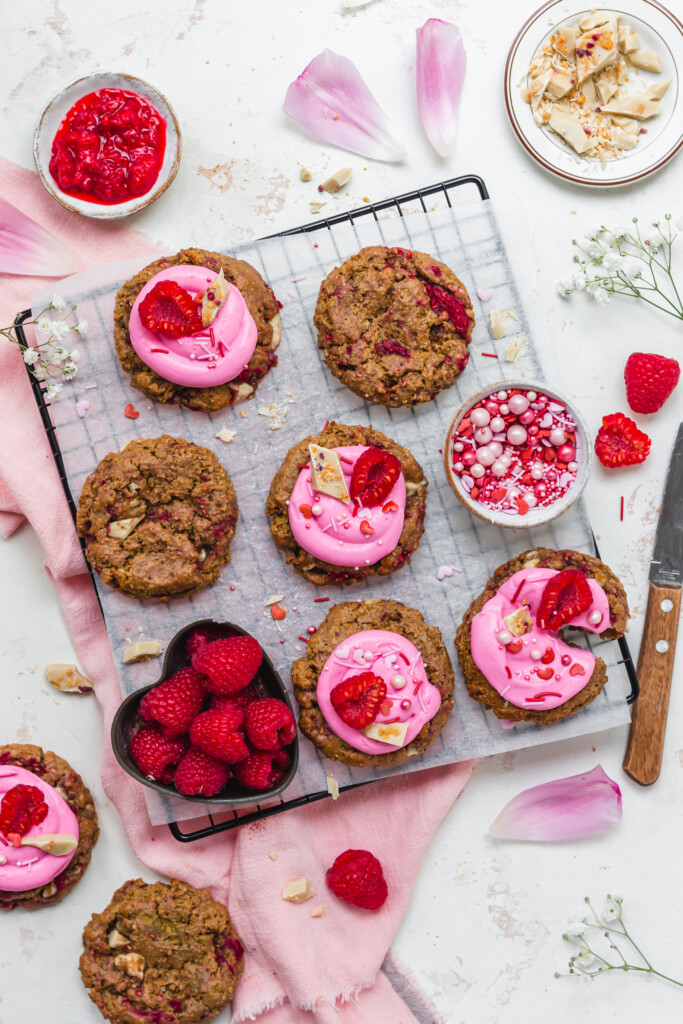 Six frosted Raspberry White Chocolate Oat Cookies with raspberries