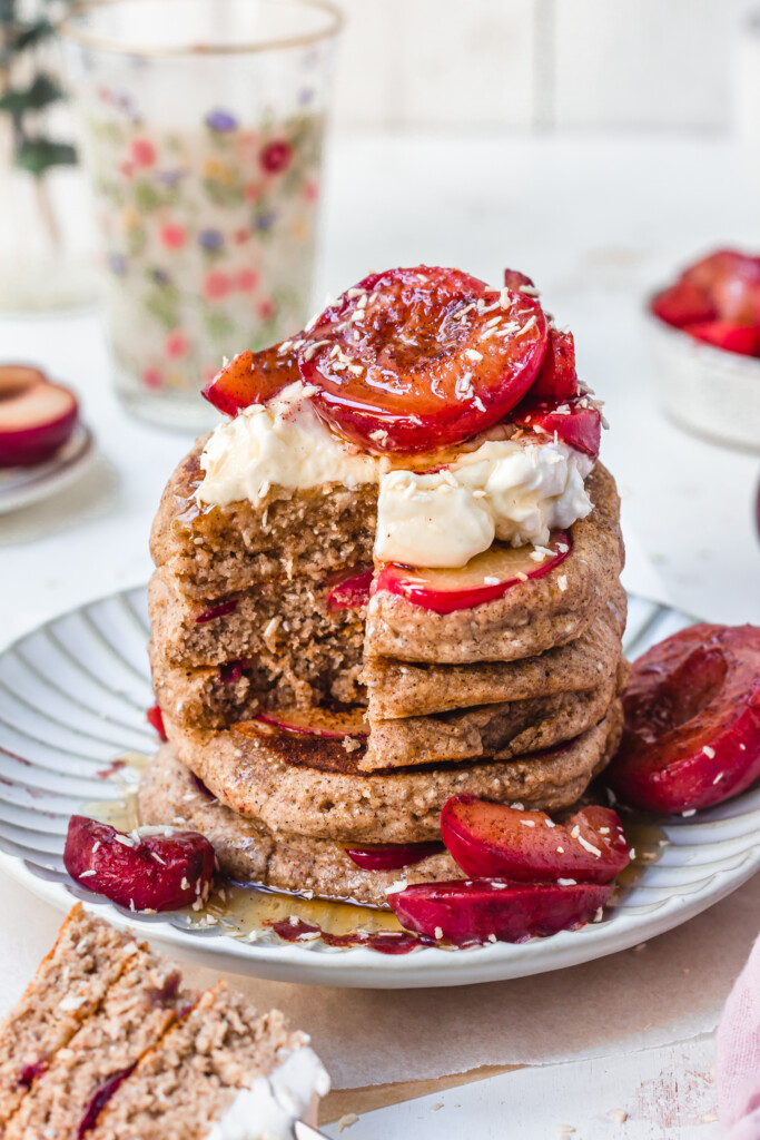 A stack of Sticky Maple Plum Pancakes with some eatten
