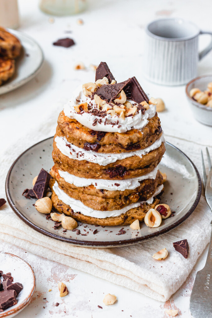 A stack of Chocolate Hazelnut Tiramisu Pancakes with cream and chocolate on top