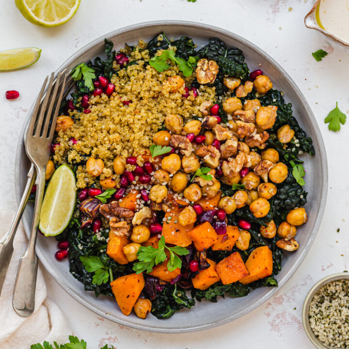 A bowl of Crispy Quinoa Squash and Kale Salad with Garlic Tahini with two forks