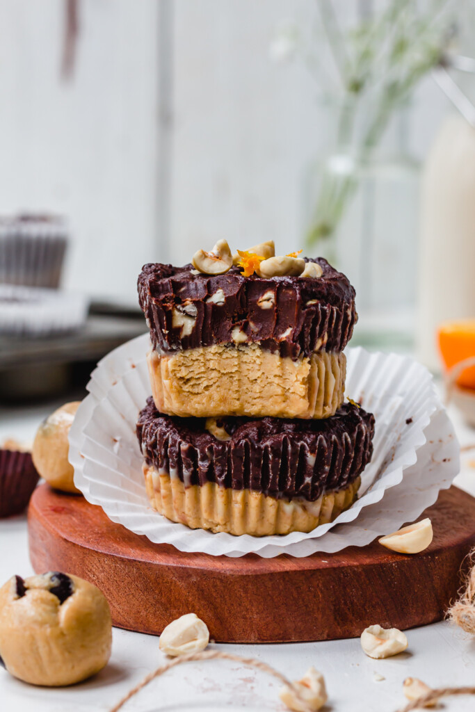 Two Chocolate Orange Cookie Dough Fudge Cups on a small brown board