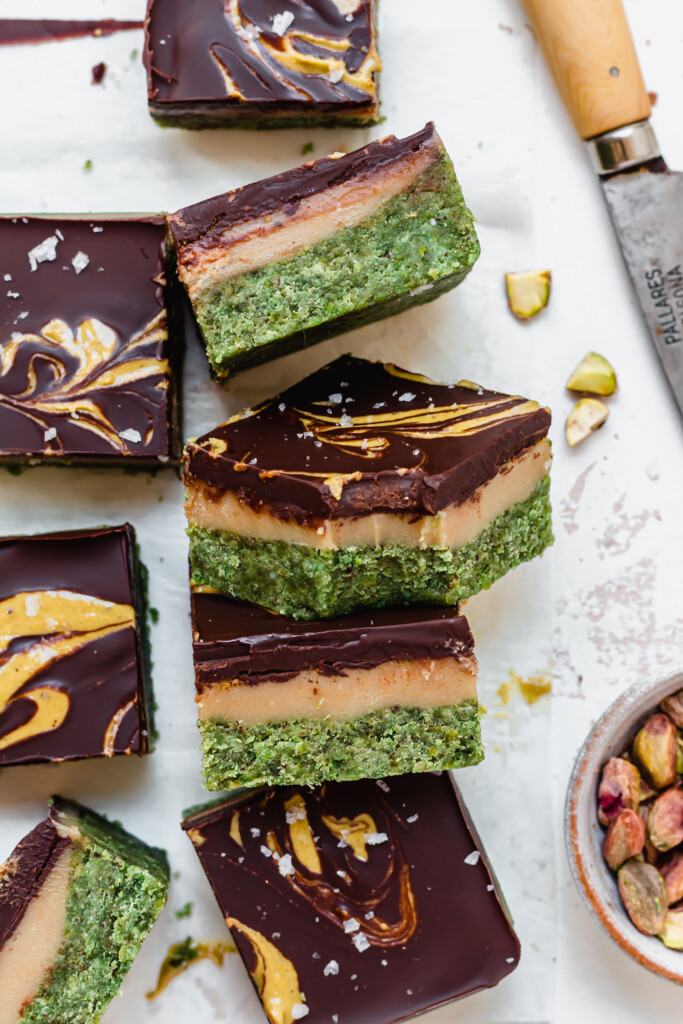 A bitten Pistachio Caramel Cake Bar with other bars on a board