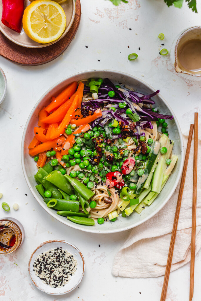 Tahini dressing over vegetables and noodles in a bowl