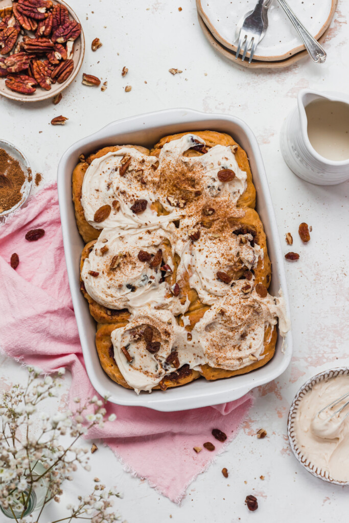 Six frosted Carrot Cake Cinnamon Rolls (Vegan) in a white dish