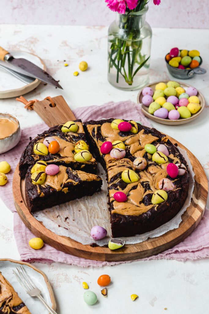 Mini Egg Peanut Butter Flourless Brownies on a board with pink linen