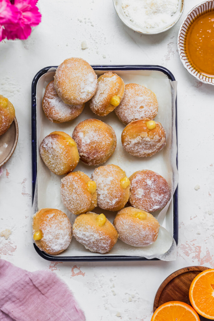 A tray of filled and un-filled Orange Curd Air Fryer Baked Vegan Donuts
