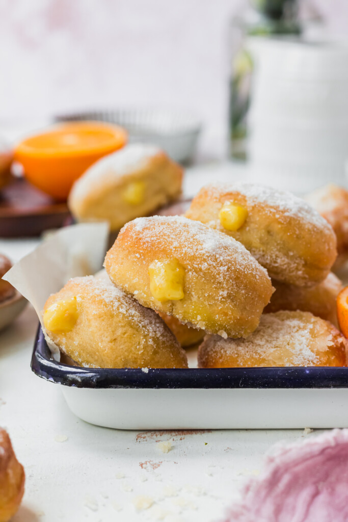 A few Orange Curd Air Fryer Baked Vegan Donuts in a white enamel dish