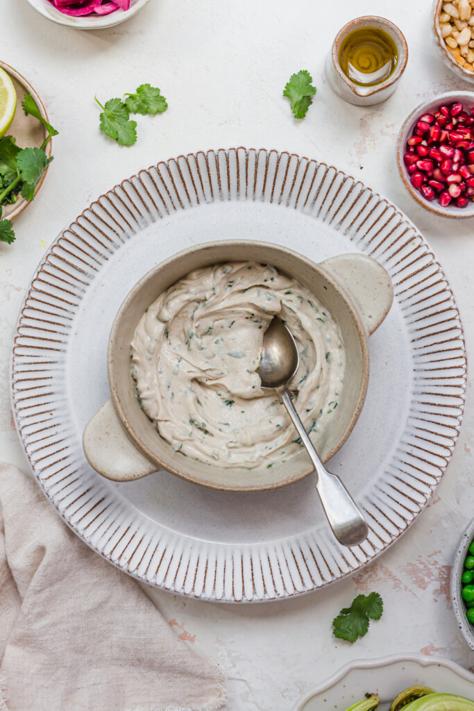 A bowl of herby whipped tahini with a spoon