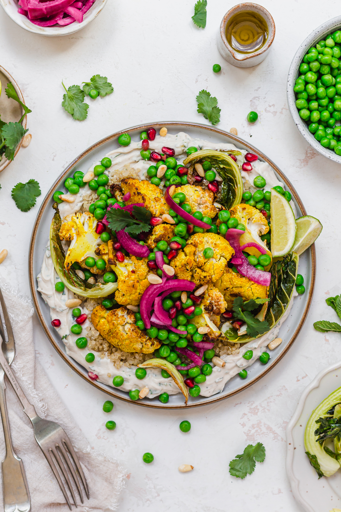 A plate of Roasted Cauliflower and Peas with Whipped Tahini with forks