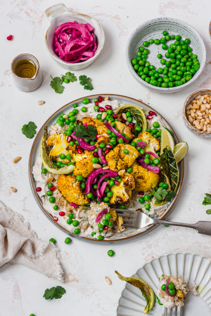 A plate of Roasted Cauliflower and Peas with Whipped Tahini with a fork