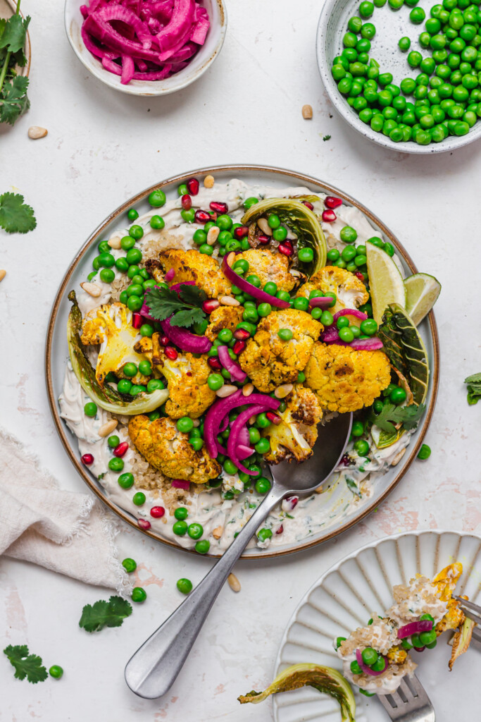 A plate of Roasted Cauliflower and Peas with Whipped Tahini with a spoon