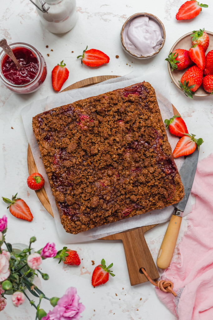 A square of Strawberry Crumb Cake on a wooden board