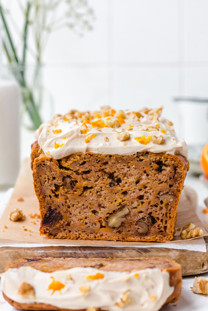 Frosted Vegan Orange Carrot Loaf Cake with one slice cut off