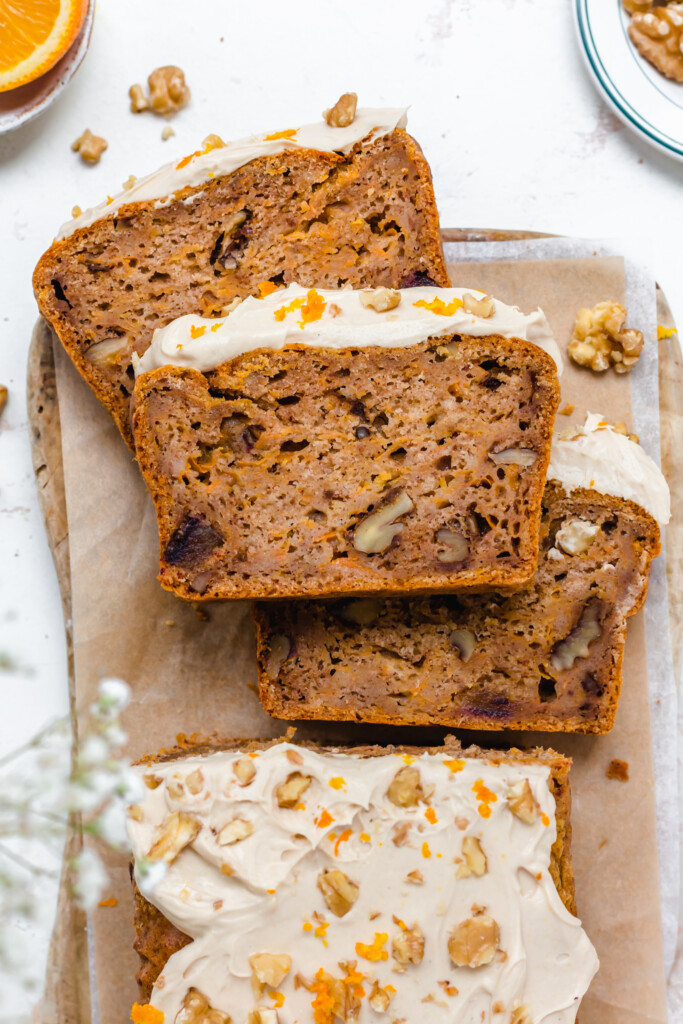 Three slices of Vegan Orange Carrot Loaf Cake on a wooden board