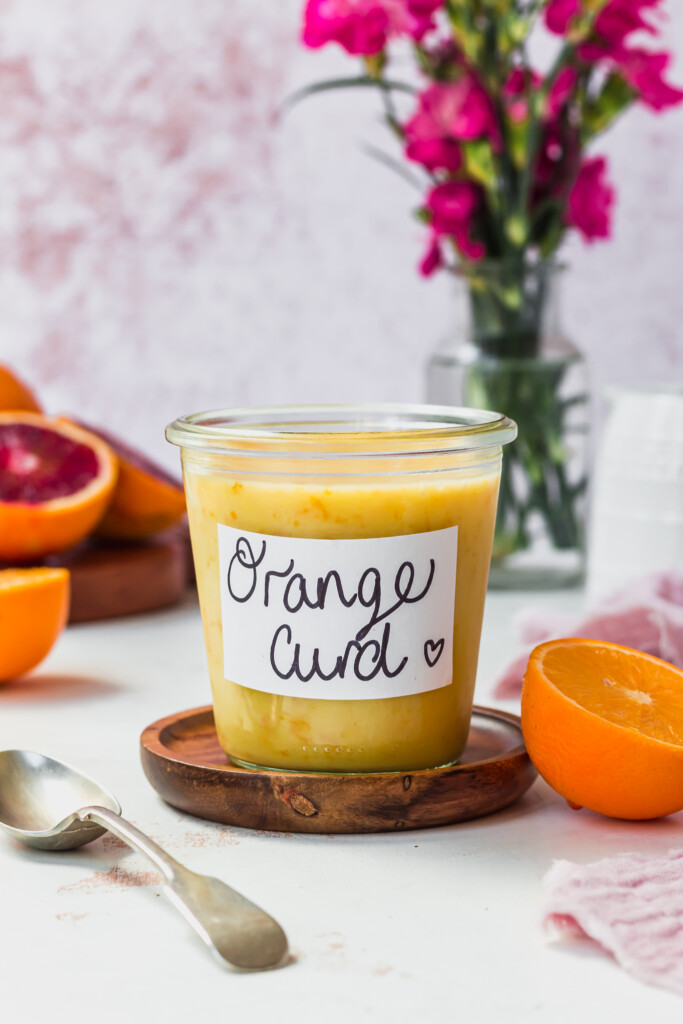 A jar of Vegan Orange Curd (No Eggs or Butter!) with a spoon and oranges