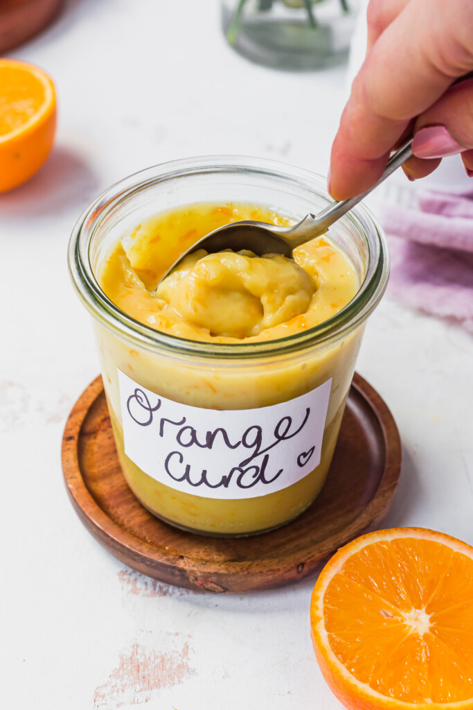 A spoon going into a jar of Vegan Orange Curd