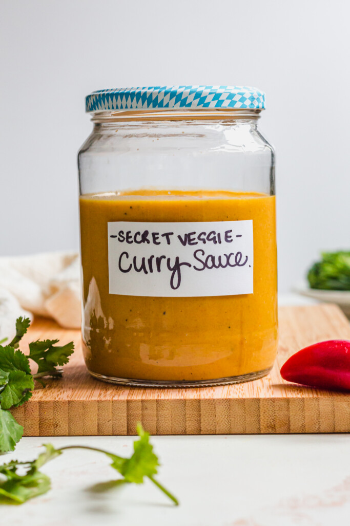 A jar of Vegetable Packed Vegan Curry Sauce with a blue lid