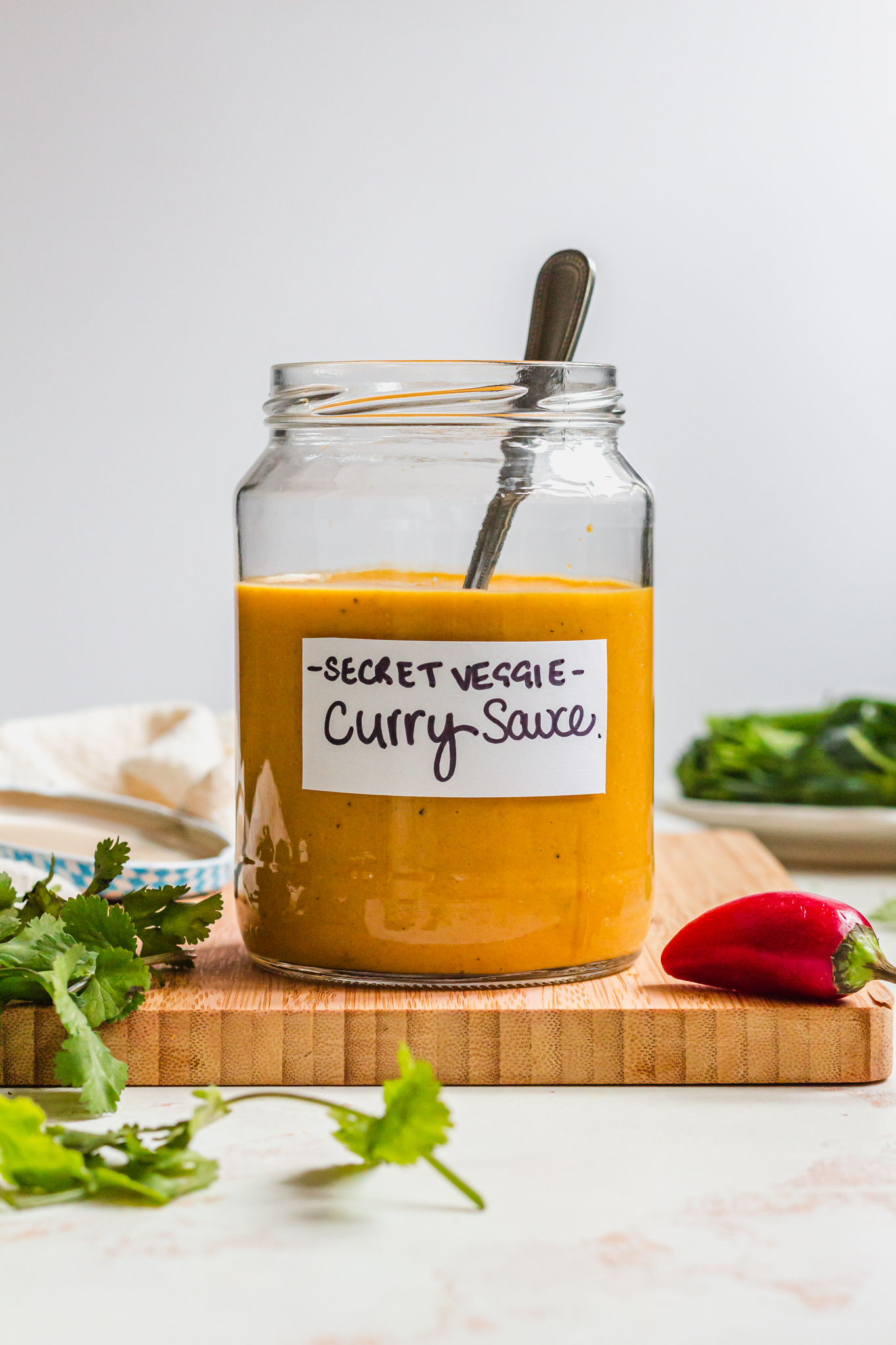 A spoon in a jar of Vegetable Packed Vegan Curry Sauce