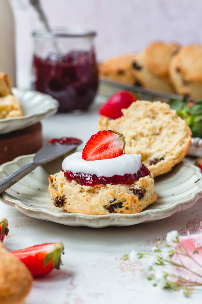 Close up of a scones with jam, cream and a straweberry