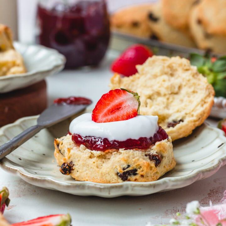 Close up of a scones with jam, cream and a straweberry