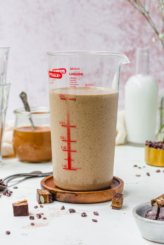 A large glass beaker of peanut butter smoothie