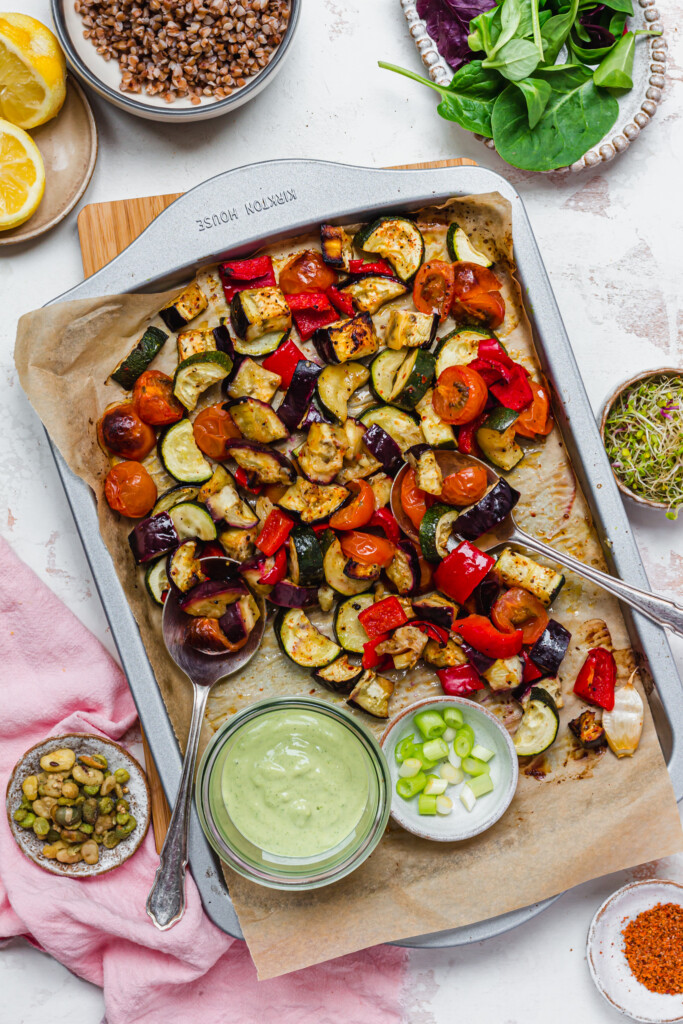 Roasted vegetables on a tray with green dressing